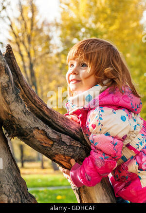 Glückliches Kind spielen im Park auf den Baum klettern Stockfoto