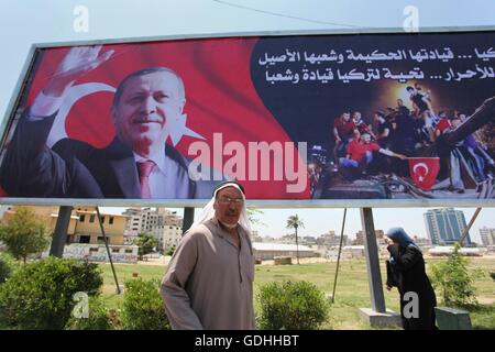 Khan Younis, Gazastreifen, Palästinensische Gebiete. 17. Juli 2016. Palästinenser gehen vorbei an ein Plakat mit einem Porträt der türkische Präsident Recep Tayyip Erdogan in Gaza-Stadt, am 17. Juli 2016. Das Schreiben in Arabisch lautet: '' Unterstützung Turkey.its kluge Führung und seine verbundenen Menschen. Sieg für die free.salute der Türkei Führer und seine Menschen ''. Türkische Behörden entrissen wieder die Kontrolle über das Land am 16. Juli nach Niederschlagung eines Militärputsches durch unzufriedene Soldaten versuchen, die Macht von Präsident Recep Tayyip Erdogan zu ergreifen, die mehr als 250 Menschen das Leben gekostet (Credit-Bild: © Ashraf Amr Stockfoto