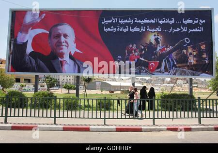 Khan Younis, Gazastreifen, Palästinensische Gebiete. 17. Juli 2016. Palästinenser gehen vorbei an ein Plakat mit einem Porträt der türkische Präsident Recep Tayyip Erdogan in Gaza-Stadt, am 17. Juli 2016. Das Schreiben in Arabisch lautet: '' Unterstützung Turkey.its kluge Führung und seine verbundenen Menschen. Sieg für die free.salute der Türkei Führer und seine Menschen ''. Türkische Behörden entrissen wieder die Kontrolle über das Land am 16. Juli nach Niederschlagung eines Militärputsches durch unzufriedene Soldaten versuchen, die Macht von Präsident Recep Tayyip Erdogan zu ergreifen, die mehr als 250 Menschen das Leben gekostet (Credit-Bild: © Ashraf Amr Stockfoto