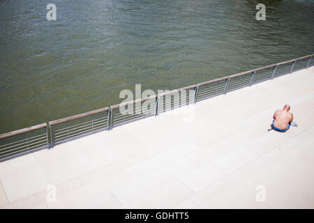 Ein Mann sonnen sich und liest ein Buch über den Rhein Boulevard in Köln, Deutschland, 18. Juli 2016. Foto: ROLF VENNENBERND/dpa Stockfoto