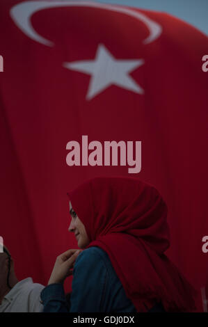 Türkische muslimische Frau mit rotem Kopftuch mit türkischer Flagge hinter die Teilnahme an einer Kundgebung pro Regierung in Istanbul Taksim Square Stockfoto