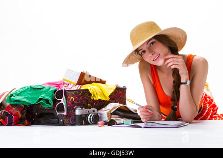 Mädchen liegt in der Nähe von überfüllten Koffer. Stockfoto