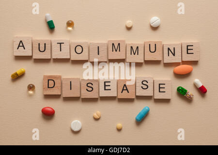Das Wort Autoimmunerkrankung mit Holzbuchstaben und Pillen um gebildet Stockfoto