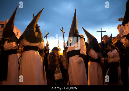 Mit Kapuze Büßer halten Stäbe mit kreuzen während einer Karwoche Prozession in Astorga, Castilla y Leon, Spanien.