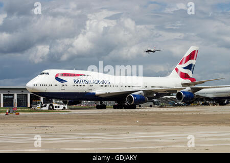 Reihe von British Airways Flugzeuge mit einem anderen Flugzeug nähert sich im Hintergrund am Flughafen London Heathrow Stockfoto