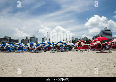 Blaue und rote Sonnenschirme mit Delano und National Hotels im Hintergrund am South Beach, Miami Stockfoto