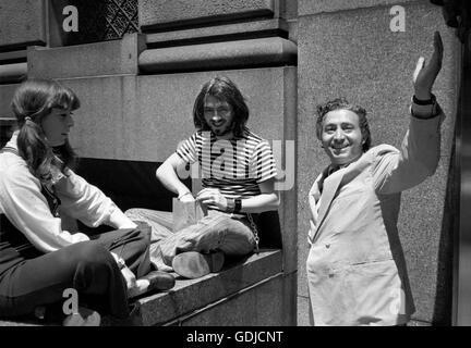 Fotograf Tony Vaccaro, rechts, winkt die Kamera neben ein paar überrascht die Menschen essen. Stockfoto