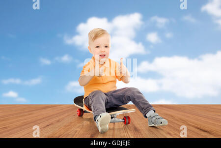 glücklich kleiner Junge auf Skateboard Daumen auftauchen Stockfoto