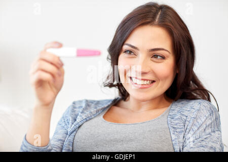 glückliche Frau Schwangerschaftstest zu Hause schauen Stockfoto