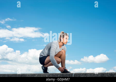 passen Sie Frau binden ihre Schnürsenkel auf ihre Turnschuhe Stockfoto