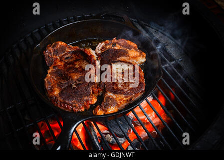 Zwei schöne Steaks auf dem Grill in einer gusseisernen Pfanne kochen. Stockfoto