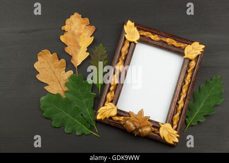 Rahmen für Fotos mit Eiche Blätter auf einem hölzernen Hintergrund. Wünsche auf eine Postkarte. Stockfoto