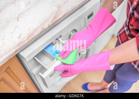 Weibliche Hände in Handschuhen Waschmaschine waschen. Close-up. Stockfoto