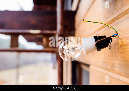 Glühbirne hängt an Seilen auf Holzwand. Stockfoto