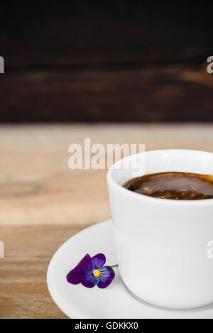 Tasse Espresso-Kaffeemaschine mit Blume auf alten rustikalen Holztisch angeordnet Stockfoto