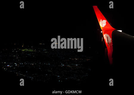 Nacht Schuss von Lion Air Logo Indonesiens größte privat geführte Fluggesellschaft, auf Flugzeugflügel, mit Lichter einer Großstadt unter in der Stockfoto