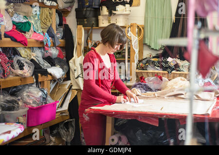Eine weibliche Schneiderin in rotes Tuch auf dem Schneidetisch messen Stockfoto