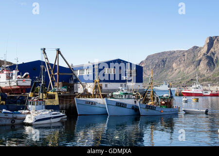 Grönländische Angelboote/Fischerboote vertäut im Hafen mit blauen Royal Greenland Fisch Fabrikgebäude hinter. Sisimiut Westgrönland Stockfoto