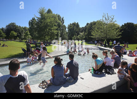 Menschen genießen die Sonne im Diana, Princess of Wales Memorial Fountain im Hyde Park, bringt London als eine Mini-Hitzewelle die heißesten Temperaturen des Jahres. Stockfoto