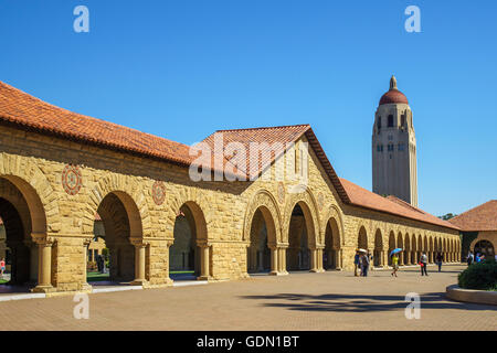 Gewölbte Sandstein und Ziegel Dach Gebäude auf dem Stanford Main Quad mit Hoover Tower im Hintergrund ein sonnigen wolkenlosen Tag Stockfoto