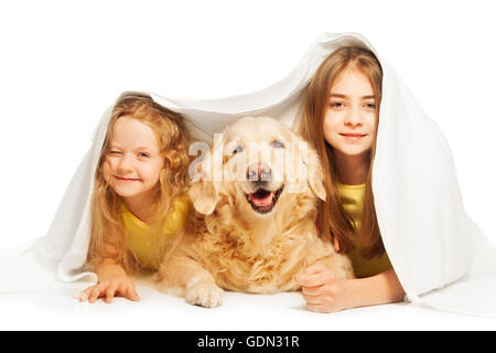 Niedlichen Mädchen versteckt unter der weißen Decke mit Hund Stockfoto