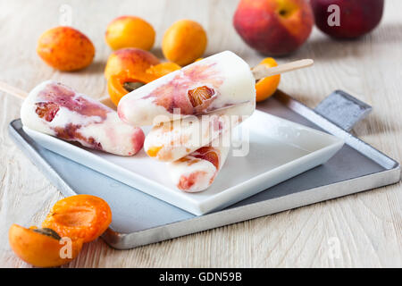 Hausgemachte Pfirsich Aprikose und orange Eis am Stiel auf weißen Teller mit frischem Obst, behandelt Sommer Stockfoto