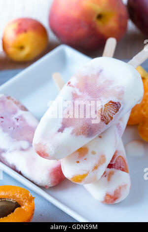 Hausgemachte Pfirsich Aprikose und orange Eis am Stiel auf weißen Teller mit frischem Obst, behandelt Sommer Stockfoto