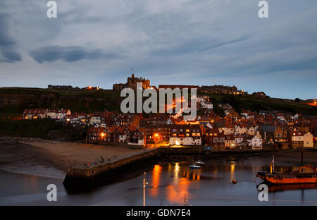 Die Ruinen von Whitby Abbey, mit dem Hafen im Vordergrund, in der Dämmerung. Stockfoto
