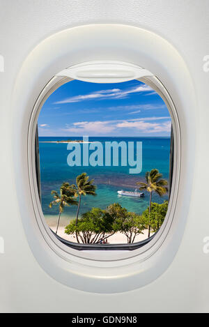 Fenster eines Flugzeugs von innen, Anzeigen auf einem tropischen Strand und Meer Stockfoto