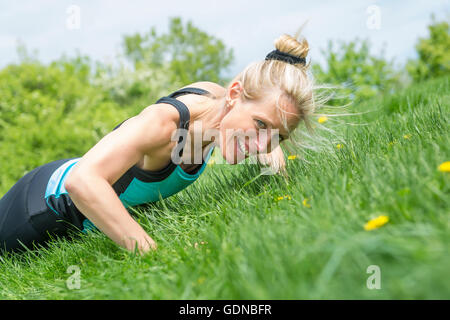 Frau macht Liegestütze im park Stockfoto