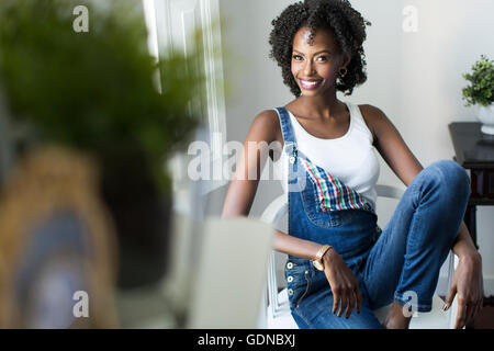 Junge afrikanische amerikanische Frau auf dem Stuhl sitzt Stockfoto