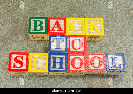 Zurück zur Schule geschrieben mit Holzbuchstaben am Steintisch Stockfoto