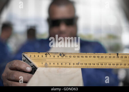 Nahaufnahme eines Tischlers Hand messen Winkel Planke in Werkstatt Stockfoto