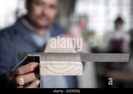 Nahaufnahme eines Tischlers Hand messen Winkel Planke in Werkstatt Stockfoto