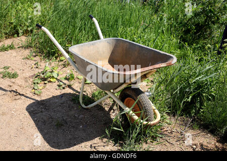 Gebäude - Jahrgangs Schubkarre eine hohe grüne Gras geworfen. Stockfoto