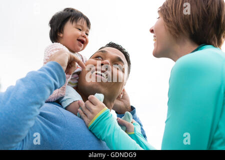 Paar spielen Huckepack Reiten mit Baby im park Stockfoto