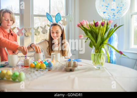 Teenager-Mädchen und Bruder färben hart gekochten Eiern zu Ostern am Tisch Stockfoto