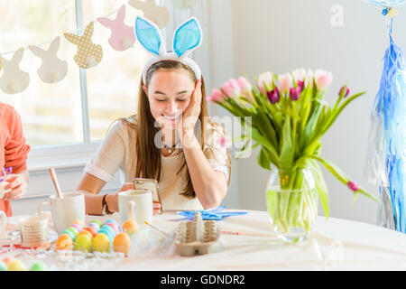 Teenager-Mädchen am Tisch Smartphone Texte zu lesen, während harte färben gekochten Eiern zu Ostern Stockfoto