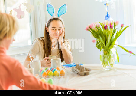Teenager-Mädchen und Bruder am Tisch färben hart gekochten Eiern zu Ostern Stockfoto