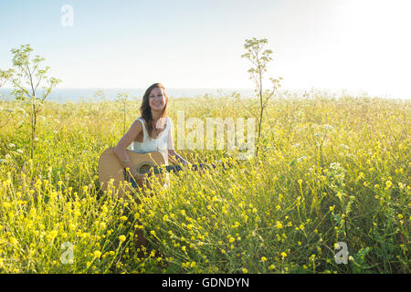 Frau mit Gitarre im Bereich der Wildblumen Stockfoto