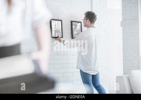 Mann, Aufhängen von Bildern im Zimmer Stockfoto