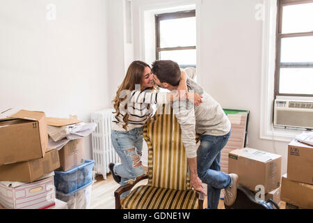 Umzug: junges Paar umarmt über Stuhl Stockfoto