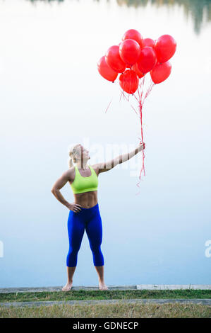 Frau mit Haufen rote Luftballons Stockfoto