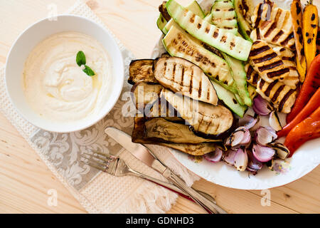 Eine Platte mit gebratenem Gemüse und eine Schale mit Tahini-Sauce, eine gesunde Ernährung-starter Stockfoto