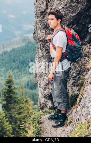 Junge stehend auf den Felsen in den Bergen und mit Blick auf ein Tal Stockfoto