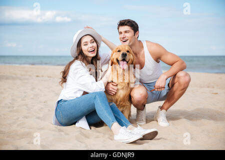 Junge attraktive Teen paar mit einem Hund am Strand sitzen Stockfoto