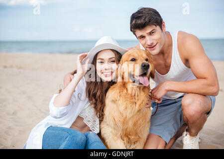 Junge attraktive Teen paar mit einem Hund am Strand sitzen Stockfoto
