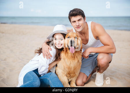 Junge attraktive Teen paar mit einem Hund am Strand sitzen Stockfoto