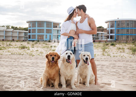 Romantische junge schöne Paar ansehen und küssen am Meer mit Hund Stockfoto