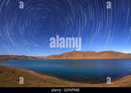 Sternspuren um den nördlichen Himmelspol über Yamdrok Lake, Tibet, China. Stockfoto